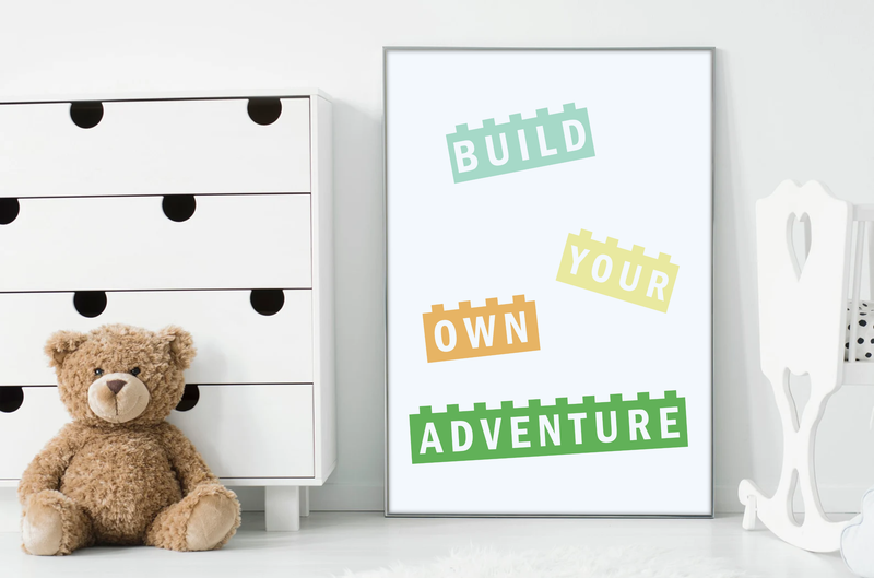 Dieses Bild zeigt dir, wie das Poster für das Kinderzimmer gerahmt aussehen würde.Dieses Poster zeigt dir vier Blöcke mit dem Spruch "Build Your Own Adventure" oder erschaffe dein eigenes Abenteuer. 